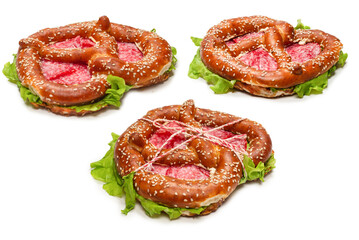 Pretzel with salami and lettuce isolated on a white background.