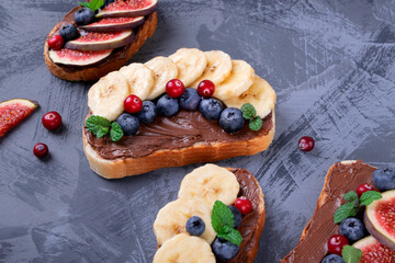 Sweet sandwiches assortment with banana, chocolate nut butter, blueberry, cranberry and fig on the gray table