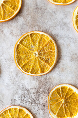Pattern with slices of dried orange on light concrete background. Food background. Top view. Flat lay.