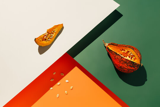 Muscat gourde with a cut slice and pulled out seeds on a four-tone background. Minimal composition with pop art aesthetic. Creative Halloween concept.