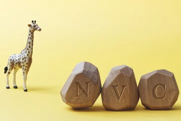 Gordijnen Letters NVC written on wooden irregular blocks with giraffe animal toy. Non-violent communication concept. © Fotema