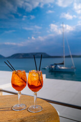 Orange drink or cocktail standing at the little table at the restaurant or cafe with sea background