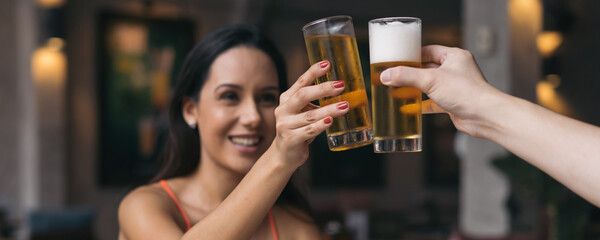 Beautiful and cheerful latin woman with hat sitting in outdoor pub restaurant clicking glass of...