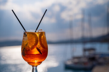 Orange drink or cocktail standing at the little table at the restaurant or cafe with sea background