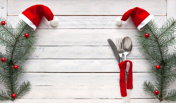 spruce branches in red caps and cutlery tied with a red scarf on a white wooden background. Christmas concept