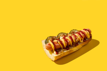 Close up of tasty sandwich. Hard shadow on a bright yellow background with copy space. American junk food concept.