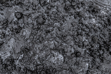 Fototapeta na wymiar Slippery frozen earth covered ice. Winter black ground after freezing rain