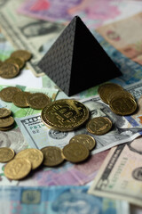 Ukrainian money, bitcoin and dollars on the background of the pyramid