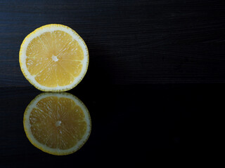 A cut lemon on a black reflective background