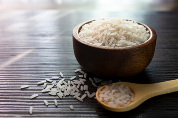 White rice in wooden bowl on dark wooden table.