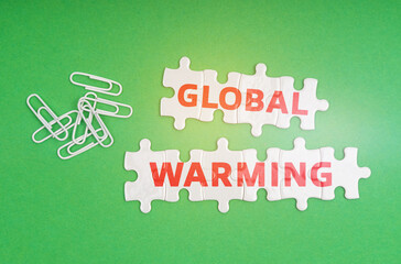 On a green background, paper clips and white puzzles with the inscription - Global Warming