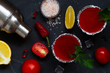 Tomato juice with salt and parsley in glass. vampiro cocktail with ingredients. Bloody Mary cocktail. Alcoholic drink with vodka, lemon and pepper on the black background. top view