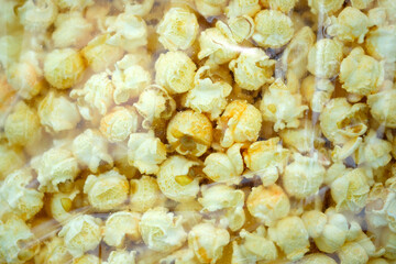Packaging Salted popcorn with cheese flavor transparent plastic bag top view. Corn grains from Argentina that are popping open. Large grains of popcorn.