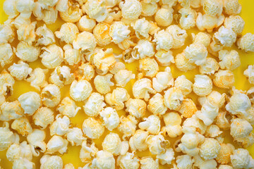 Salted popcorn with cheese flavor on a yellow background top view. Corn grains from Argentina that are popping open. Large grains of popcorn.