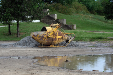 Old rusty mobile concrete mixer on the street. Yellow Reduced Concrete Mixer. Metal equipment for...