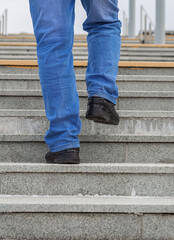 Fototapeta na wymiar Male legs in jeans and boots climb the stairs.