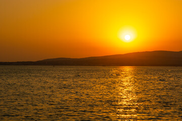 Evening sky with the setting sun over the sea and mountain. Spectacular sunset over the sea.
