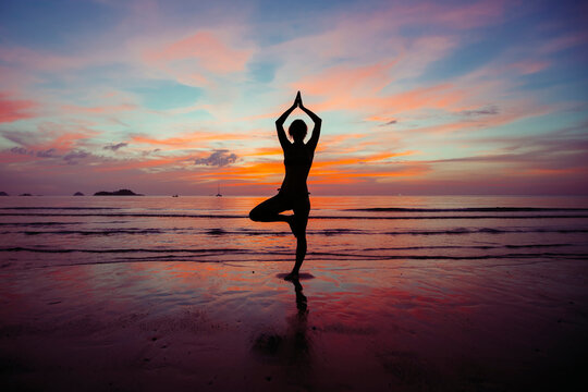 Silhouette of Yoga woman meditation near the ocean beach.