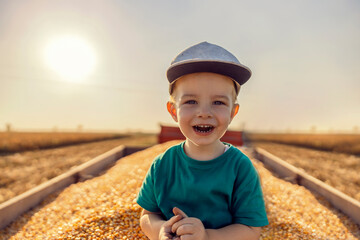 Cute little farmer boy posing on a tractor full of corn grains after harvest on the cornfield. Cute...