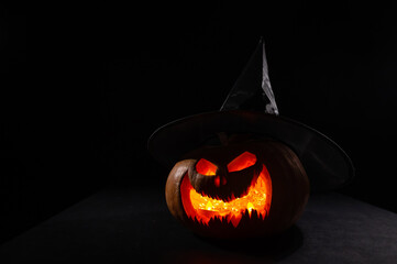 Glowing pumpkin in a witch hat in the dark. Jack o lantern.