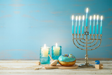 Jewish holiday Hanukkah concept with menorah, candles and dreidel on wooden table. Background for...