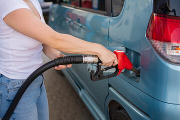 Woman refueling car with gasoline at self-service gas station.