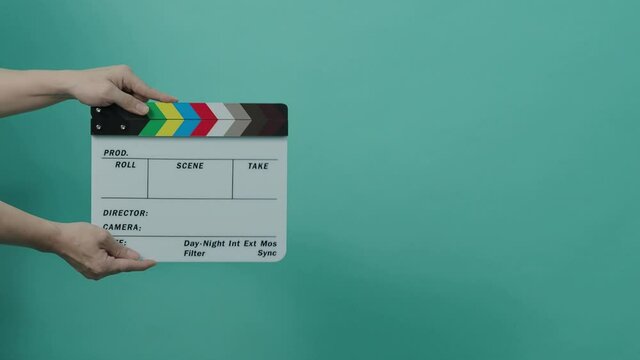 Clapperboard hitting. Movie film slate. close up hand clapping empty film slate on blue or green screen color background. in and out film slate cutting for video production. film or Movie shooting.