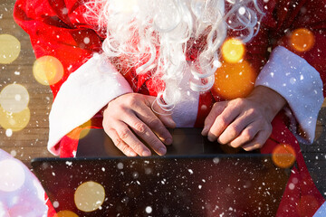 Santa Claus with a laptop and a gift in his hand. Order gifts for Christmas and new year through...