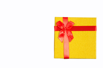 The golden gift box is tied with a red ribbon with a bow on a white background and isolated. Copy...
