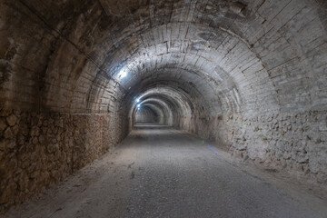 Interior of a lighted and empty tunnel, with dirt and gravel floors