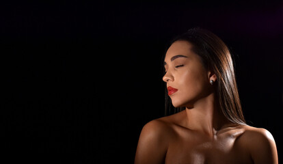 portrait of a beautiful young woman with closed eyes and bare shoulders, isolated on black background with space for text