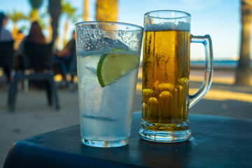 cerveza rubia y gin con tónica en una mesa de chiringuito a la orilla del mar, momento de relax