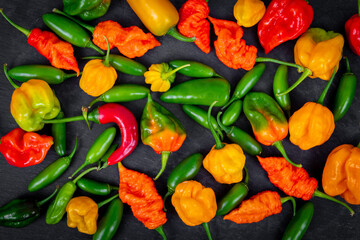 assorted hot peppers chiles on black background