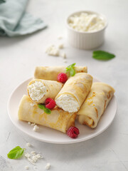 Crepes with cottage cheese, strawberry and mint. Thin pancakes with fillings. Pancake week or Shrovetide. Pancakes flapjack thin cake curd filling crepe cottage cheese