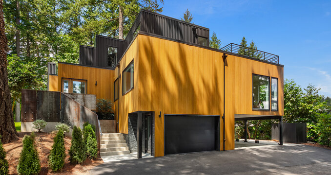 Beautiful exterior of modern home with linear design and elegant use of wood and metal, surrounded by trees on bright sunny day.