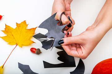 women's hands carve black paper bats, Halloween,