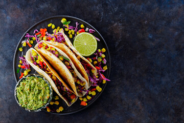 Vegetarian tacos with sweet corn, purple cabbage and tomatoes on a black plate. Tacos with...
