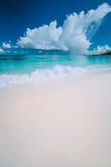 Beautiful white wave rolling towards tropical sandy beach. Gorgeous fluffy clouds above blue sea. Seychelles Grand Anse, La Digue, Seychelles