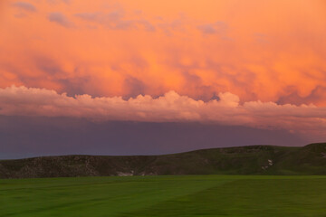 Landscape of rain clouds turning orange at sunset.