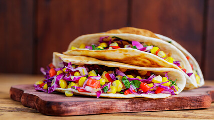 Vegan tacos with various vegetables on a cutting board. Tacos with sweet corn, purple cabbage and...