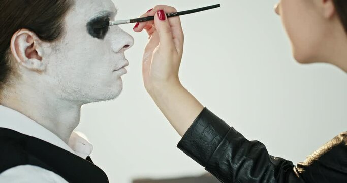 The process of make-up of the actor of the horror film of the dead spirit of the guy make-up of the white face creating an image in the studio by a make-up artist