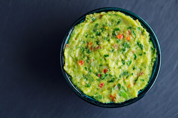 Bowl of guacamole on a dark background. Traditional mexican dip sauce guacamole. Traditional mexican food. Copy space. Top view