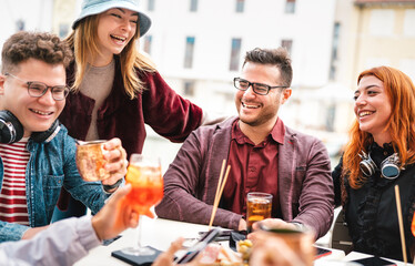 Friends having fun drinking at open air bar after work - Life style concept with young people enjoying time together sharing cocktails on happy hour at city center - Bright warm filter