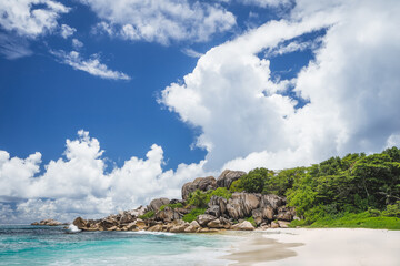 Obraz premium Grand Anse tropical beach in La Digue, Seychelles. Famous granite rock formations and white clouds above