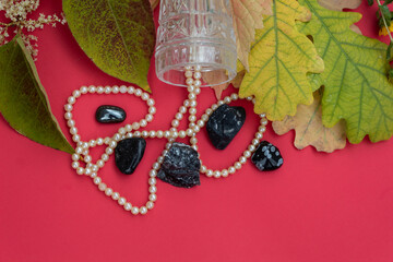 On a red background lie autumn leaves, a necklace and semi-precious stone