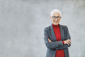 A Senior Business Woman Standing With Crossed Arms And Looking At Camera