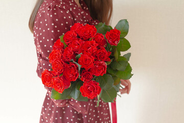 Very nice young woman holding big and beautiful bouquet of fresh roses  red  colors, cropped photo, bouquet close up