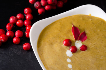 Macro Image of Delicious Squash Thanksgiving Soup Decorated with Rowan Berries and Cream