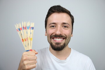 Happy young man showing mikado pick up sticks
