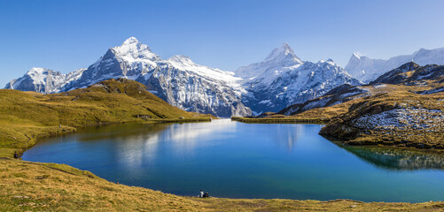 Fototapeta na wymiar Panorama of Bachalpsee at the First peak over Grindelwald with the snow-covered Alps summit Wetterhorn, Schreckhorn, Eiger at the background